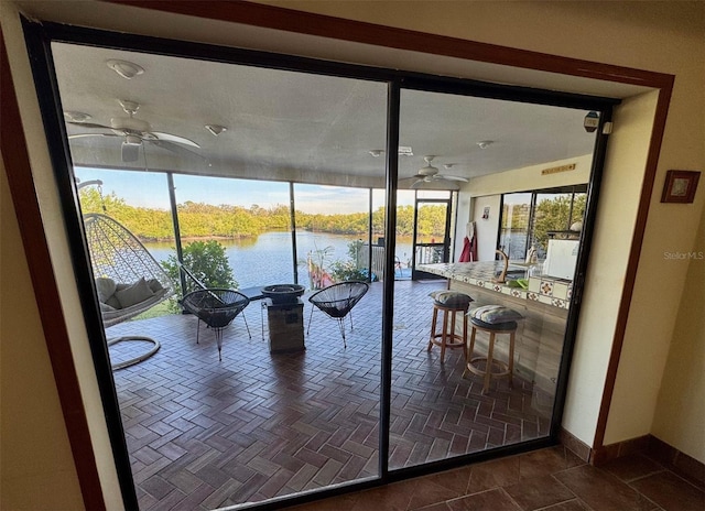 doorway to outside featuring a water view, ceiling fan, and dark tile patterned floors