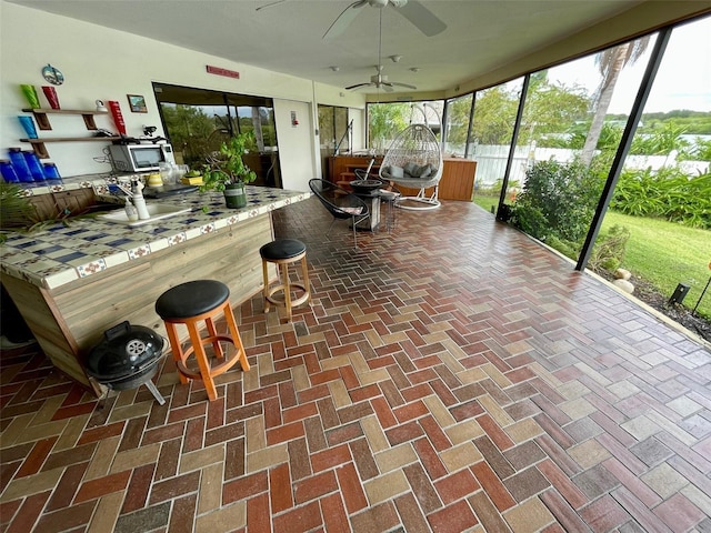 unfurnished sunroom featuring ceiling fan and plenty of natural light