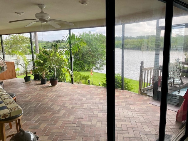 sunroom with ceiling fan, a wealth of natural light, and a water view