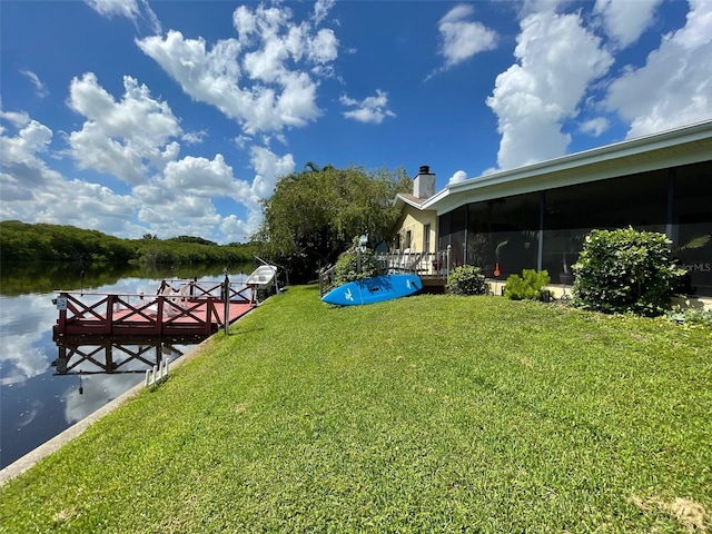 view of yard with a sunroom, a water view, and a dock