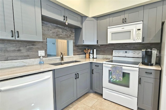 kitchen with gray cabinets, sink, light tile patterned floors, and white appliances