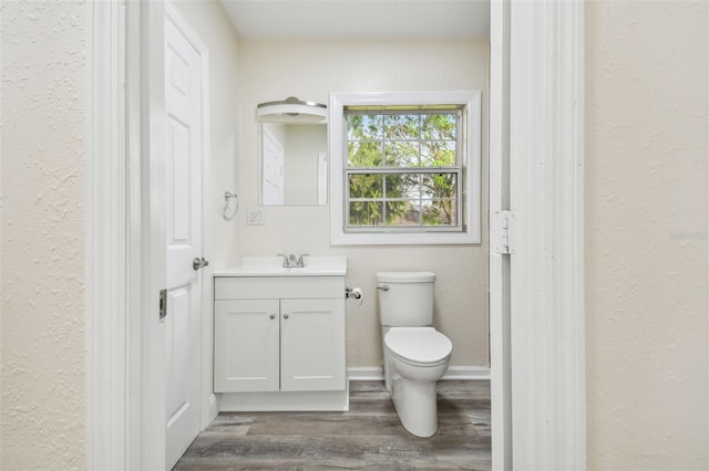 bathroom with hardwood / wood-style floors, vanity, and toilet