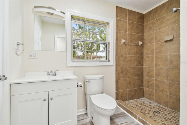 bathroom featuring hardwood / wood-style flooring, vanity, toilet, and a tile shower