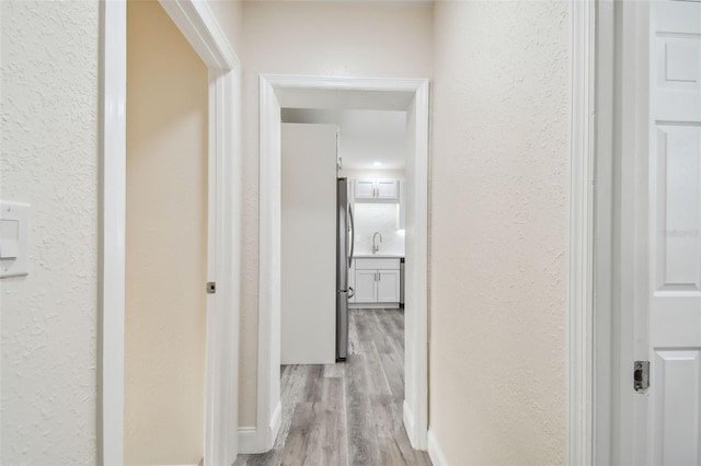 hallway with light hardwood / wood-style floors and sink