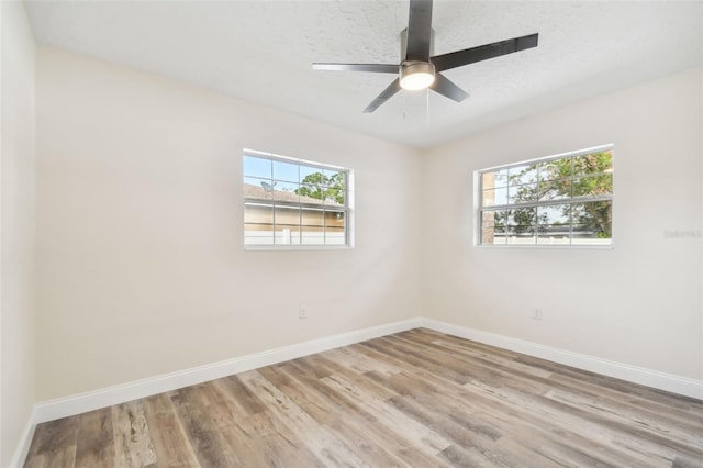 spare room with ceiling fan, a healthy amount of sunlight, light wood-type flooring, and a textured ceiling