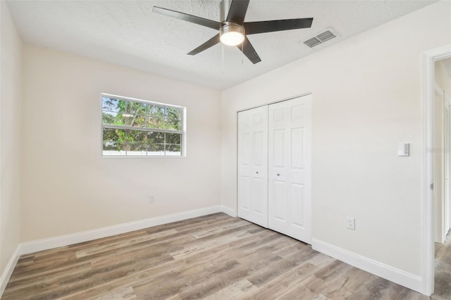 unfurnished bedroom featuring ceiling fan, a closet, a textured ceiling, and light hardwood / wood-style flooring