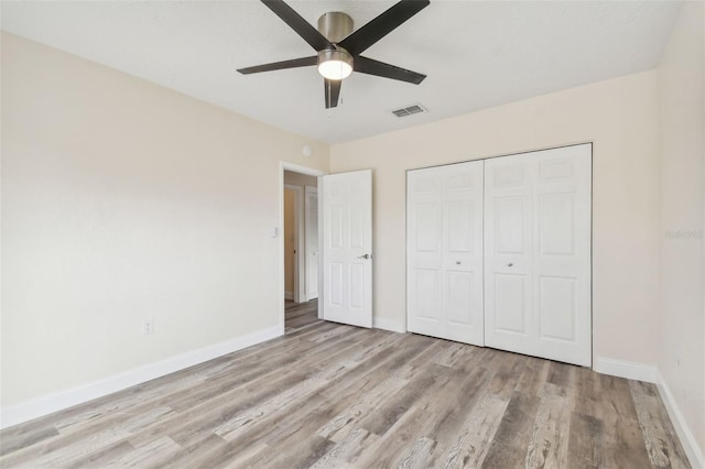 unfurnished bedroom featuring ceiling fan, light wood-type flooring, and a closet