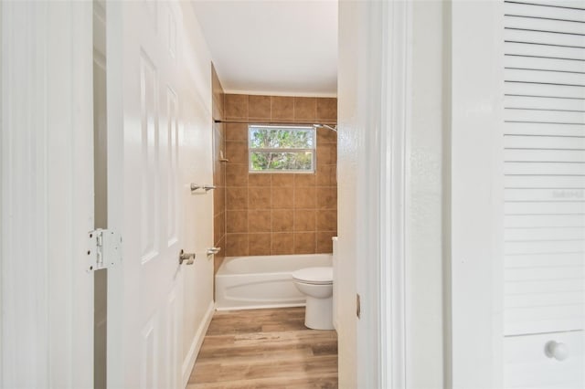 bathroom with tiled shower / bath, wood-type flooring, and toilet