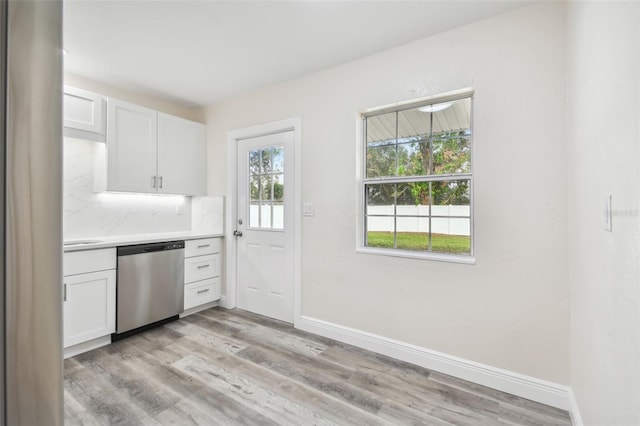831 Searcy Ave, Sarasota, FL 34237 - kitchen with stainless steel dishwasher, light countertops, white cabinetry, light wood-type flooring, and decorative backsplash