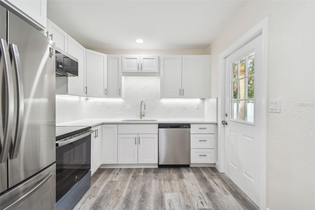 kitchen with white cabinets, appliances with stainless steel finishes, and light hardwood / wood-style flooring