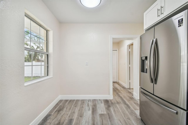 kitchen featuring stainless steel fridge, white cabinets, and light wood-type flooring