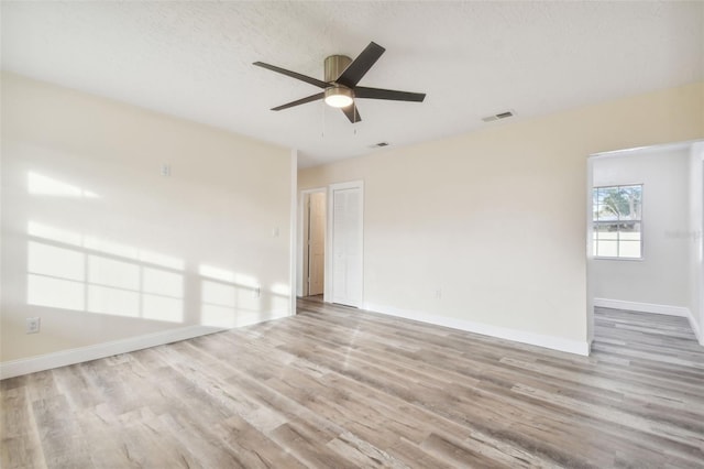 empty room with ceiling fan, light hardwood / wood-style floors, and a textured ceiling