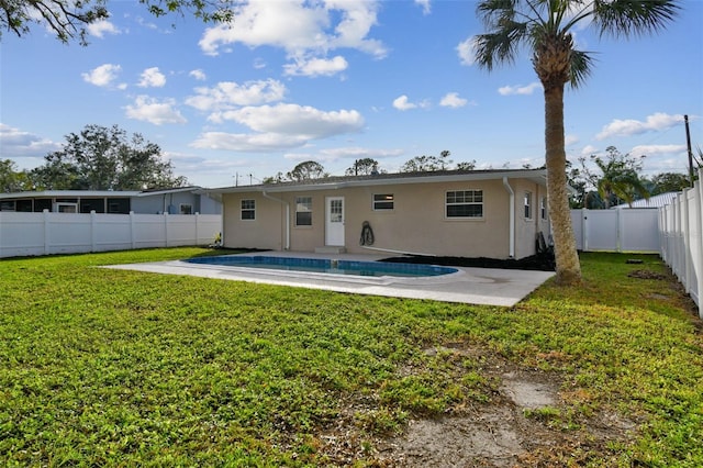 back of house with a fenced in pool, a patio area, and a lawn