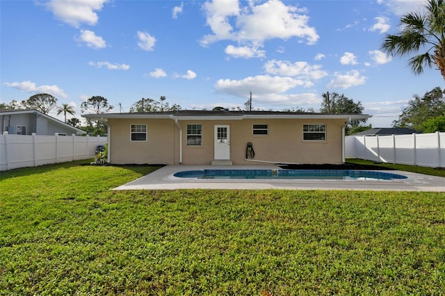 rear view of property with a lawn and a fenced in pool