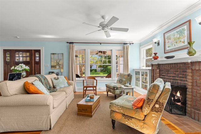 living room with a brick fireplace, crown molding, and ceiling fan