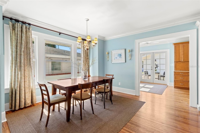 dining area with french doors, an inviting chandelier, ornamental molding, and light hardwood / wood-style floors