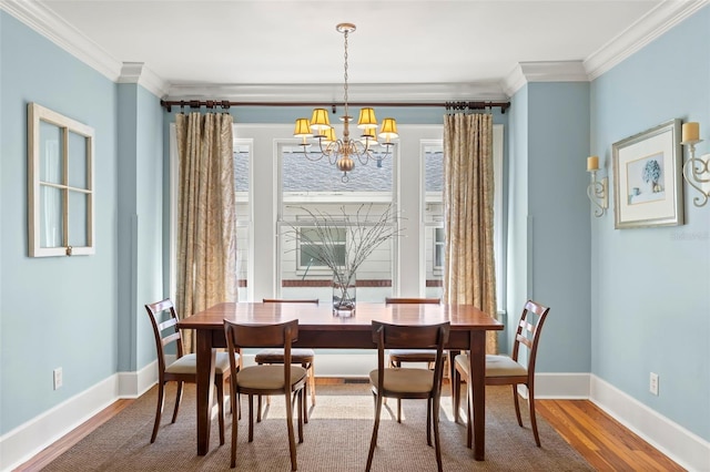 dining room with hardwood / wood-style flooring, ornamental molding, and a notable chandelier