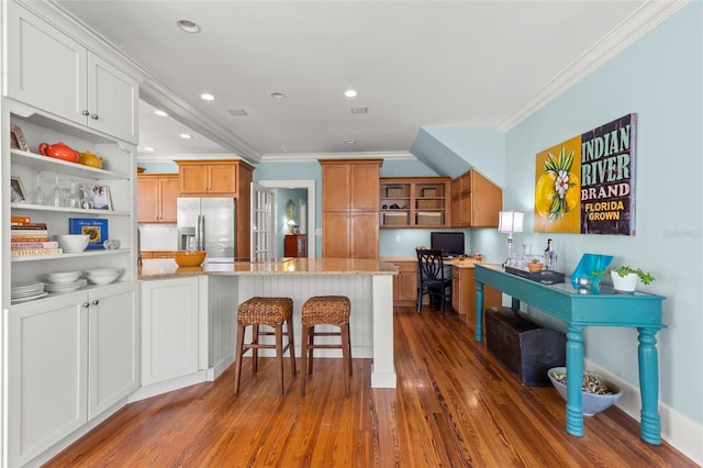 kitchen featuring white cabinetry, crown molding, stainless steel fridge, and light stone countertops