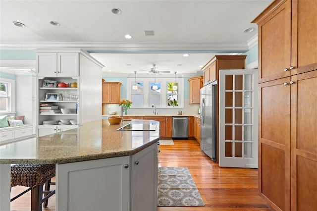 kitchen with appliances with stainless steel finishes, white cabinetry, sink, a breakfast bar, and crown molding