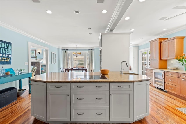 kitchen featuring wine cooler, an island with sink, sink, and ornamental molding