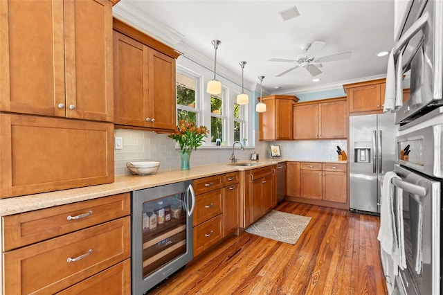 kitchen with decorative light fixtures, beverage cooler, ornamental molding, and appliances with stainless steel finishes