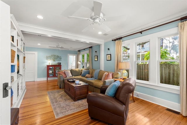 living room with a healthy amount of sunlight, crown molding, light hardwood / wood-style floors, and ceiling fan