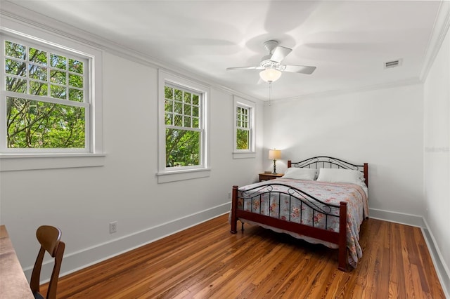 bedroom featuring ceiling fan, crown molding, multiple windows, and hardwood / wood-style floors