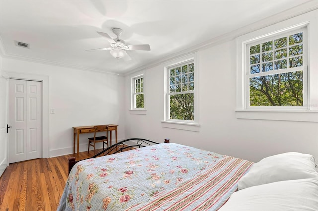 bedroom featuring ceiling fan, hardwood / wood-style flooring, a closet, and ornamental molding