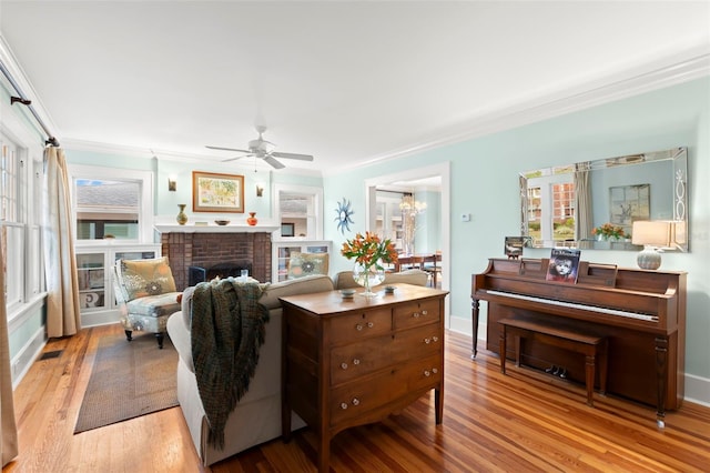 living area with light wood-style floors, crown molding, a fireplace, and visible vents