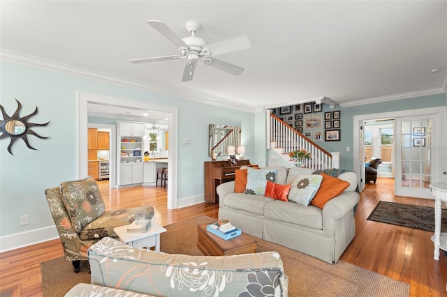 living area featuring light wood-style floors, baseboards, stairway, and ornamental molding