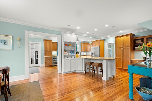 kitchen featuring brown cabinetry, a kitchen bar, stainless steel refrigerator with ice dispenser, and light countertops