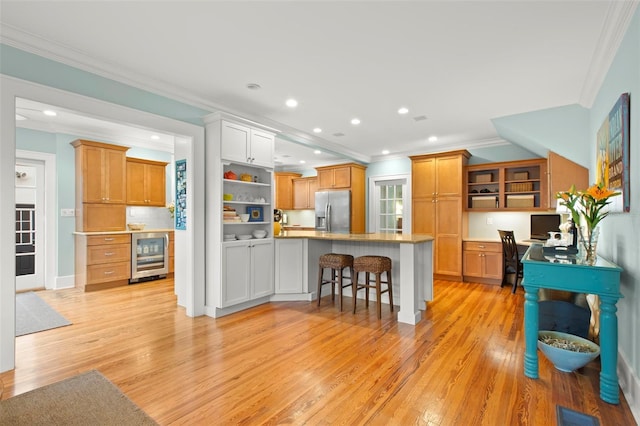 kitchen with beverage cooler, brown cabinetry, stainless steel fridge with ice dispenser, a breakfast bar area, and light countertops