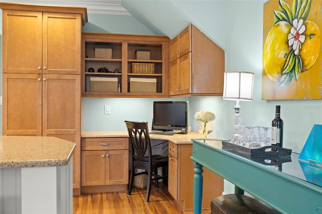 office featuring lofted ceiling, built in desk, and light wood finished floors