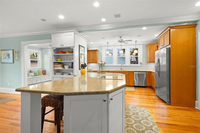 kitchen featuring appliances with stainless steel finishes, white cabinets, a kitchen breakfast bar, and a center island