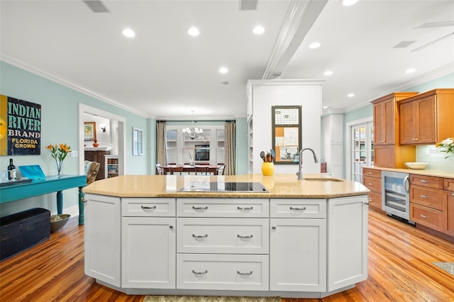 kitchen with beverage cooler, black electric stovetop, a sink, and white cabinetry