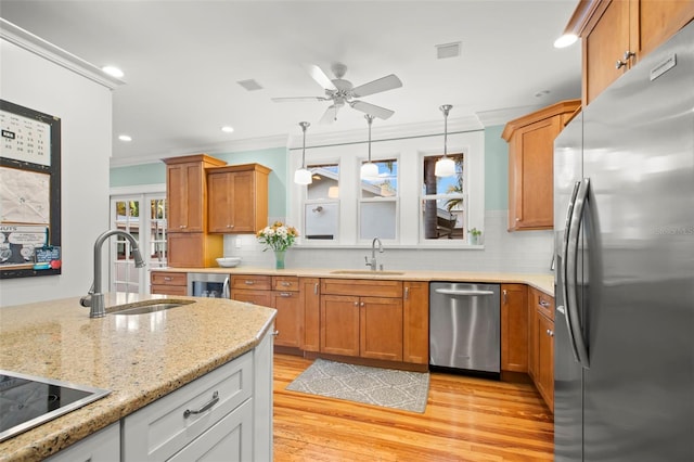 kitchen with appliances with stainless steel finishes, a sink, light stone counters, and white cabinets