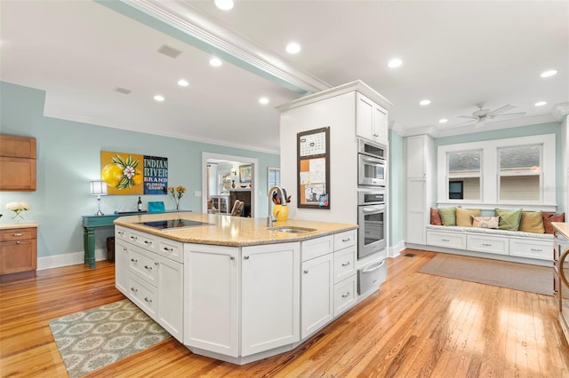 kitchen featuring black electric cooktop, ornamental molding, white cabinets, and a sink