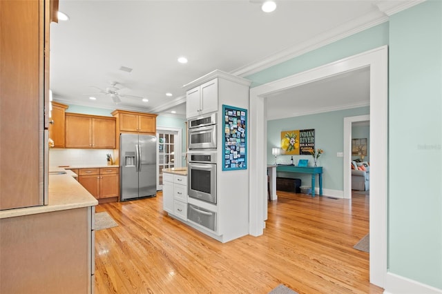 kitchen with ornamental molding, light countertops, appliances with stainless steel finishes, and white cabinets