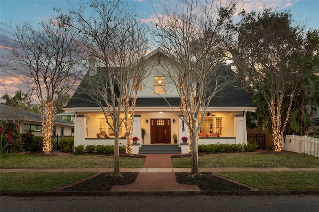 view of front of property with a shingled roof, fence, a front lawn, and stucco siding