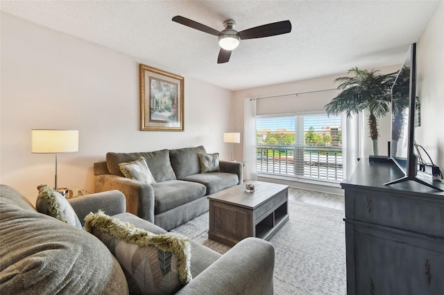 living room featuring ceiling fan, a textured ceiling, and light hardwood / wood-style floors