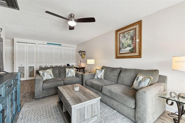 living room with ceiling fan, a textured ceiling, and light hardwood / wood-style floors