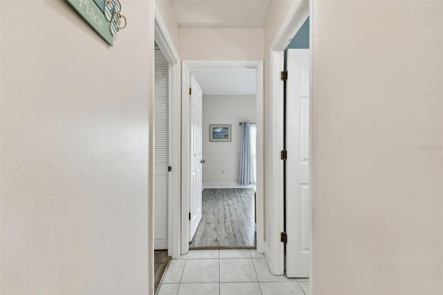 corridor featuring a textured ceiling and light tile patterned floors