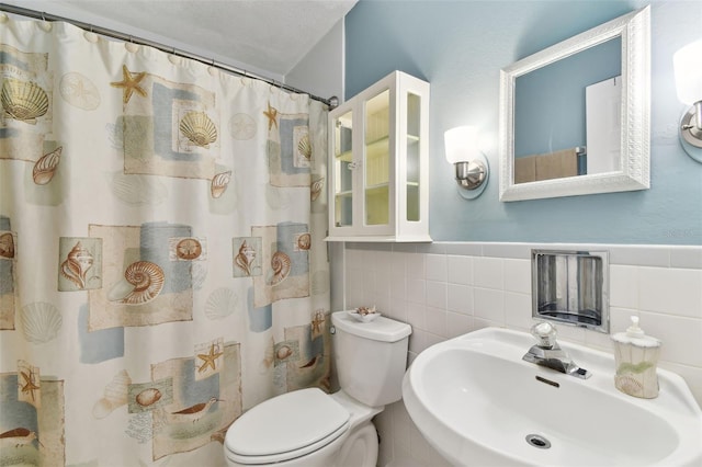 bathroom with sink, tile walls, a shower with shower curtain, and toilet