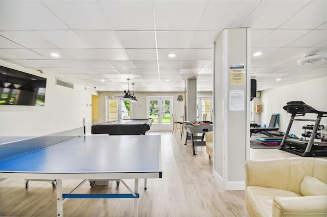 playroom with a drop ceiling, light wood-type flooring, and french doors