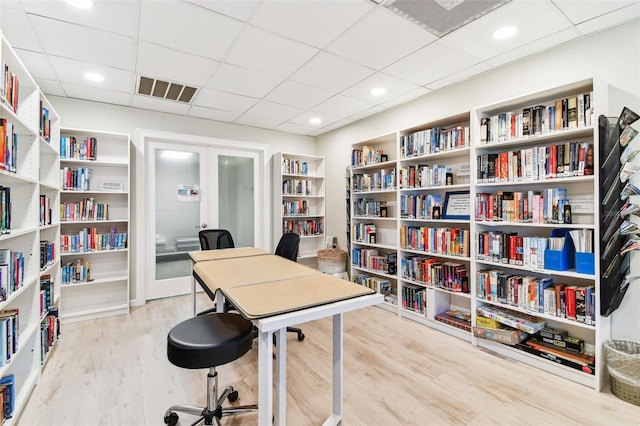 home office with french doors, light hardwood / wood-style floors, and a drop ceiling