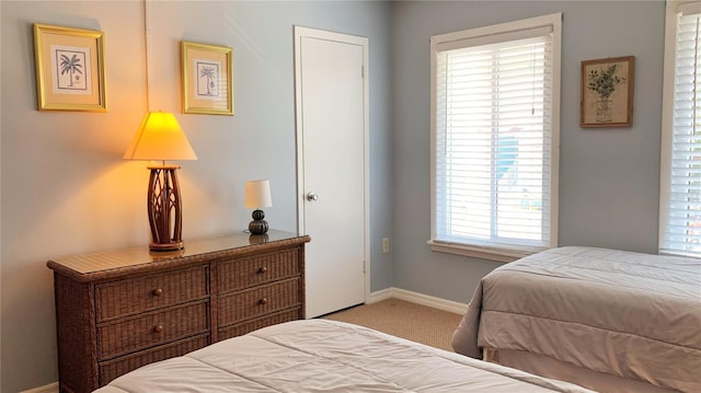 bedroom with light colored carpet and multiple windows