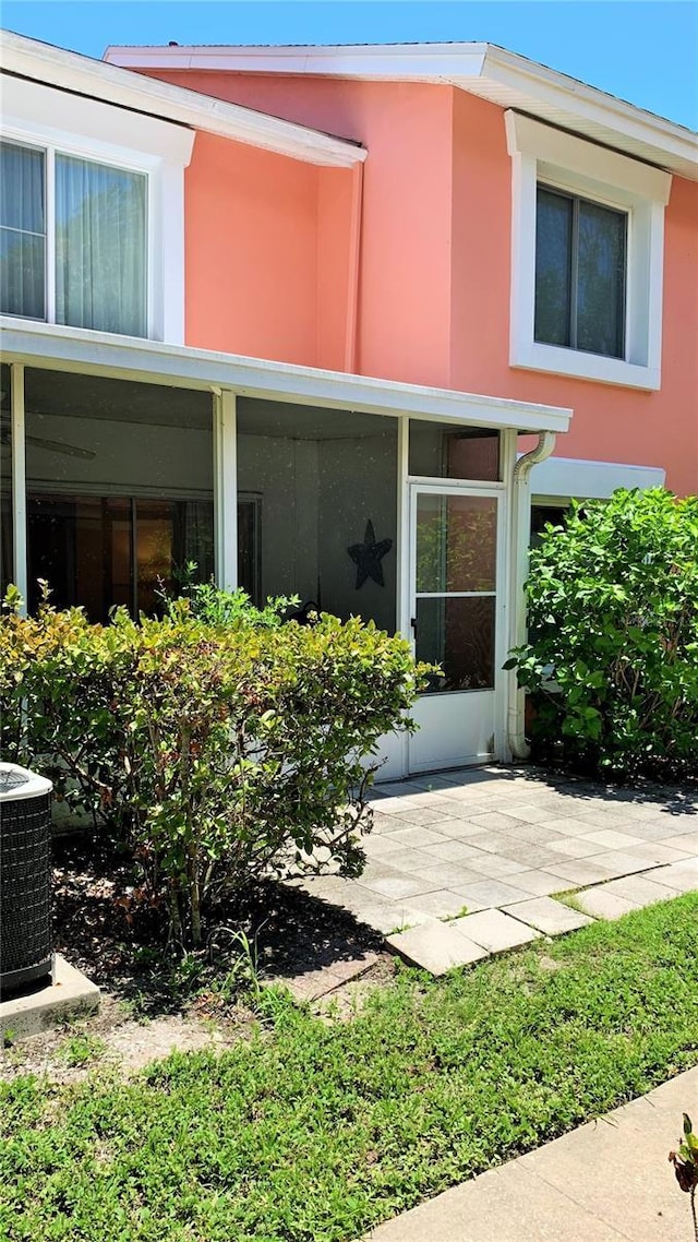 view of exterior entry with a patio area and central AC unit