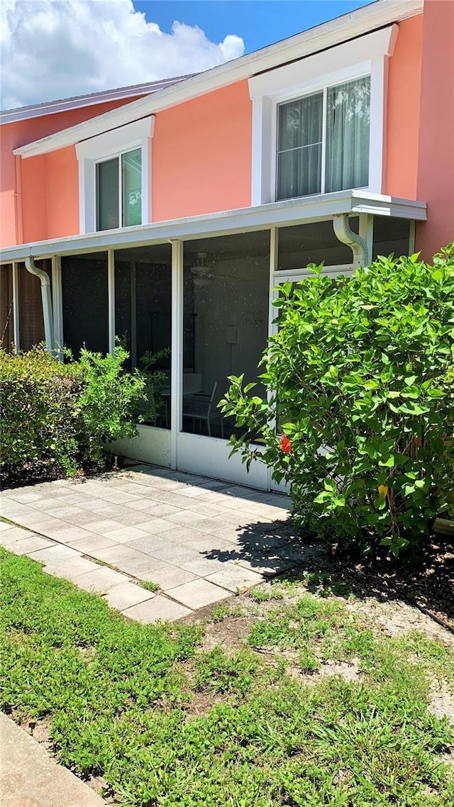 view of property exterior with a patio area and a sunroom