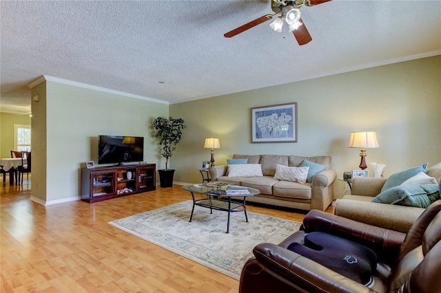 living room featuring ceiling fan, ornamental molding, a textured ceiling, and light wood-type flooring