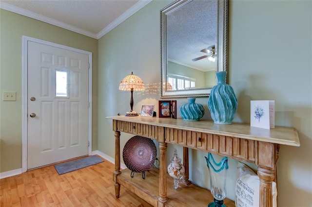 entrance foyer featuring hardwood / wood-style flooring, ornamental molding, ceiling fan, and a textured ceiling